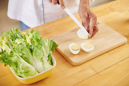 Man Cutting Boiled Eggs When Making Caesar Salad At Home