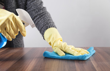Hand cleaning wooden table at home.