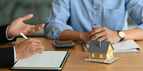 Cropped image of Real estate agent offer house insurance or house ownership to smart man in blue shirt. at the modern wooden table. Signing on agreement, Broker/Seller/Dealer concept.