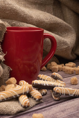 Red ceramic tea mug, cookie sticks with chocolate and white icing on a wooden background. Close up.