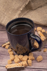 Dark blue ceramic tea mug, cookie sticks with chocolate and white icing on a wooden background. Close up.