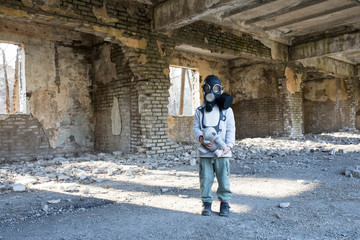 Fototapeta na wymiar child in a gas mask in a destroyed building.