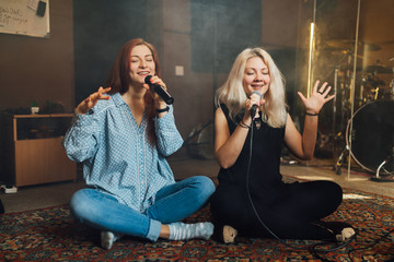 Two young woman sitting singing a duet