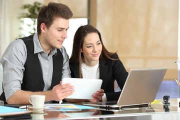 Two employees comparing tablet and laptop content