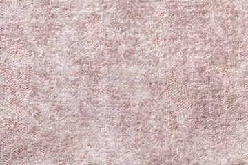 Light beige fluffy background of soft, fleecy cloth. Texture of brown textile backdrop with shiny pattern, closeup