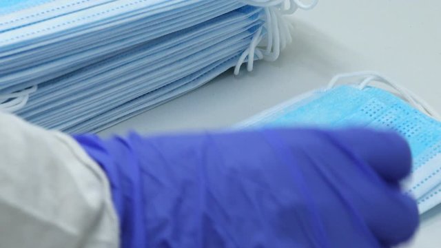 stacking surgical medical face mask for personal protective equipment against virus bacteria infection a hand in nitrile exam gloves  doctor, nurse, healthcare worker, scientist hospital clinic scene