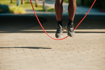 Feet of sportsman jumping with skipping rope