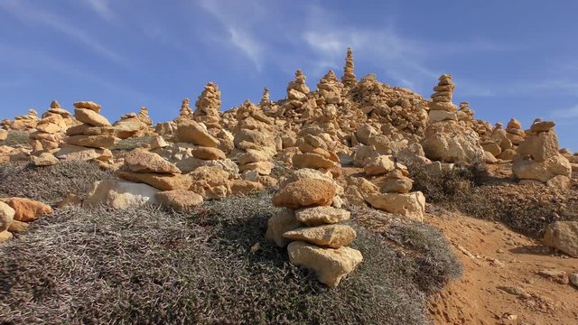 Pyramids made of stones on a low stone hill. Bright blue sky, beautiful day.