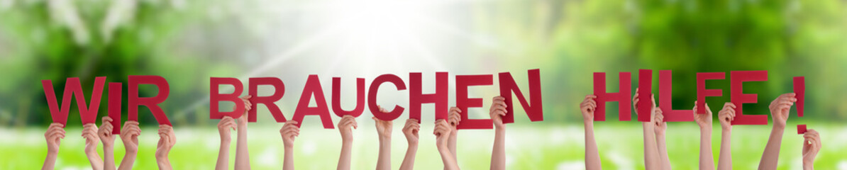 People Hands Holding Colorful German Word Wir Brauchen Hilfe Means We Need Help. Sunny Green Grass...