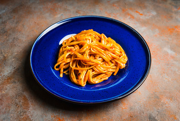 Traditional pasta with tomato sauce in blue plate on the rustic background. Selective focus.