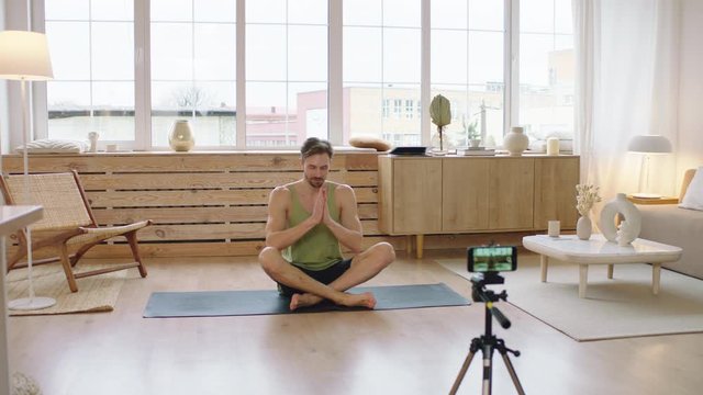 Fit Caucasian male recording a blog or streaming yoga workout from home. Stay home, quarantine life. Shot on ARRI Alexa Mini with Cooke S4 lens