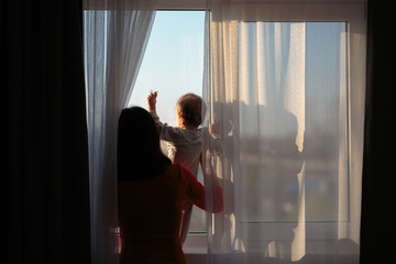 Mother and Baby Looking Out The Window During Covid-19 Pandemic Time