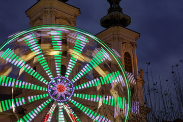 Moving ferris wheel in front of Mariahilfer Church spire, Graz, Austria