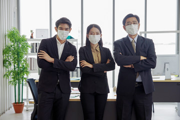 Asian businessmen and businesswoman are wearing a mask at workplace to prevent the corona virus outbreak.