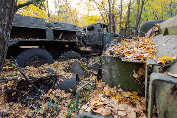 Broken down military truck with lots of scrap metal in overgrown police compound in Pripyat,...