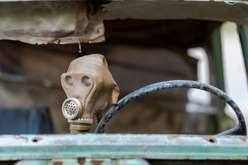 Old soviet gas mask draped on steering wheel of broken down car