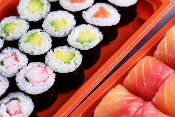 Sushi maki with salmon, shrimp and avocado, sushi philadelphia in a take away plastic container.