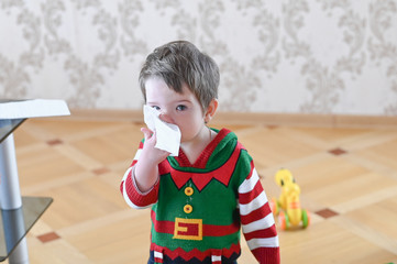 Portrait of a sick boy cleaning his nose with a napkin. Flu season concept