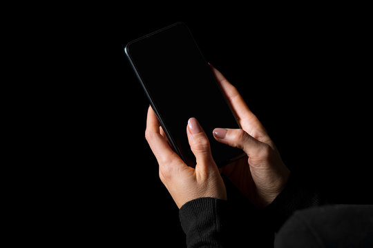 Person typing something on mobile phone with a blank screen, photo isolated on black background