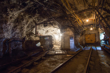 Fototapeta na wymiar Underground gold mine tunnel with rails and wagon