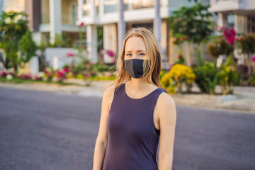 Fototapeta premium Fashionable black medical mask with filter in the city. Coronavirus 2019-ncov epidemic concept. Woman in a black medical mask. Portrait of a woman with expressive eyes during a virus or disease