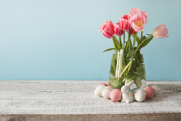 Wicker basket with easter eggs and pink tulips. Spring easter blue background with space for text.