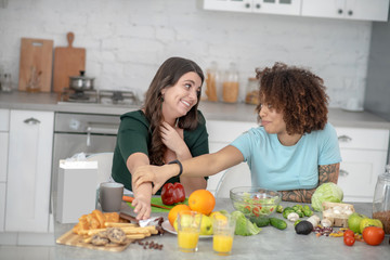 Two young girlfriends chatting in the kitchen.