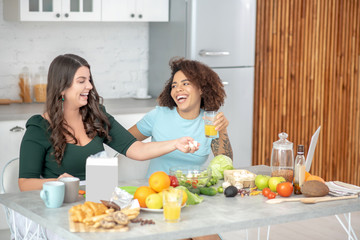 Two young women happily chatting at the kitchen table.