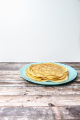 Delicious pancakes lie on blue plate. Pancakes poured with honey on wooden background. Place under the text. Stock photo.