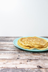 Delicious pancakes lie on blue plate. Pancakes poured with honey on wooden background.