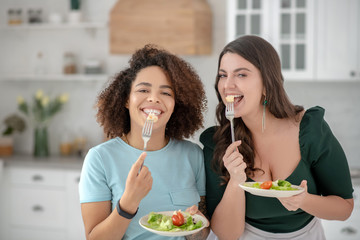 Two young pretty women eating vegetarian salad.