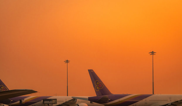 BANGKOK, THAILAND-FEBUARY 20, 2019 : Thai Airways Airlines. Commercial airplane parked at the airport with orange sunset sky. Global aviation business crisis from coronavirus. Air transportation.