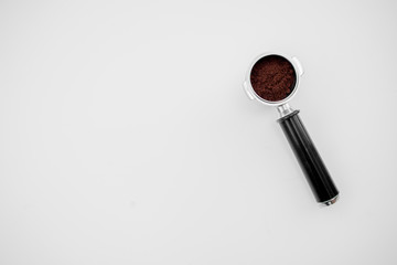 Metal holder from the coffee machine with ground coffee inside on the light background