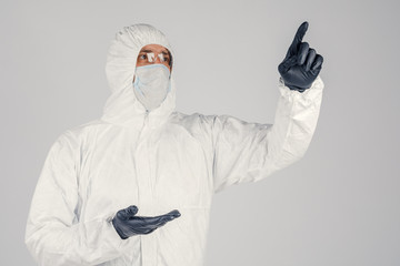 Fototapeta na wymiar A human epidemiologist in a disposable anti-epidemic antibacterial isolation suit shows hand gestures on a white background. Epidemic and medical concept