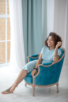 Stylish pretty woman with tattoos sitting in a chair.