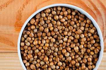 Coriander grains shot large on a wooden background. Background for spices and cuisine.
