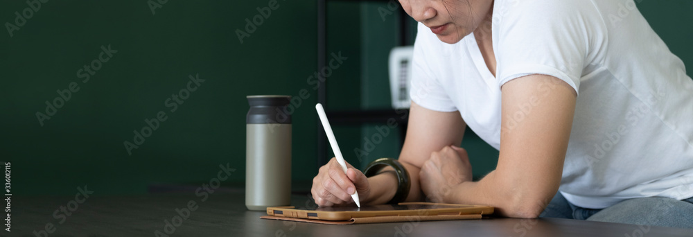 Aufkleber asian woman writing on tablet on table at home.work from home while coronavirus outbreak.leave space