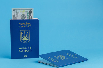 100 dollars banknote inside Ukrainian passport one passport lies next to a blue background close-up traveling business