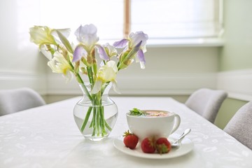 Strawberry tea on table, with vase of irises flowers