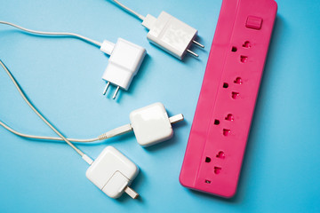 Top view of White mobile charger plugs with pink extension power strip on light blue PVC texture background ,enery management and save electricity power technology concept
