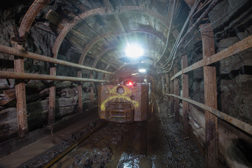 Naklejka premium Electric locomotive in underground gold mine shaft tunnel