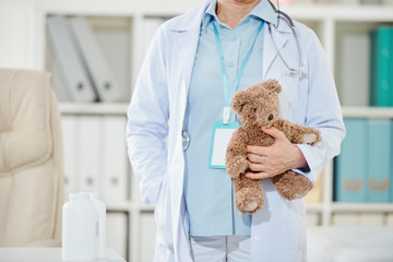 Cropped image of female pediatrician holding teddy bear and waiting for patient