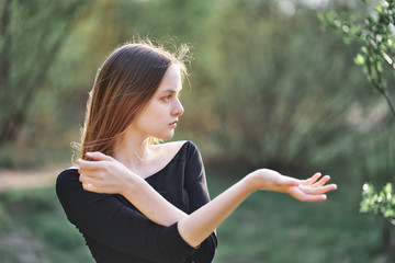 Girl teenager with long hair gesticulating with her hands on a background of nature.