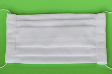 Handmade fabric reusable medical face mask isolated on green background.