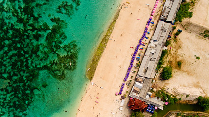 Fototapeta premium Top view of a Pandawa beach with many umbrellas and people relaxing. Bali, Indonesia.