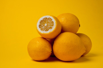 Ripe and juicy lemons shot on a yellow background. Background for vitamins and fruits.