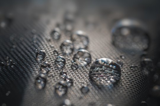 Many water drops on waterproof impregnated fabric of black umbrella.