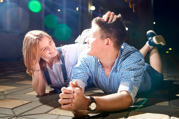 Young hipster fun couple at the night city street and light flush on black background