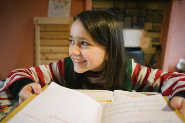 child girl at home performs homework by writing in the notebook