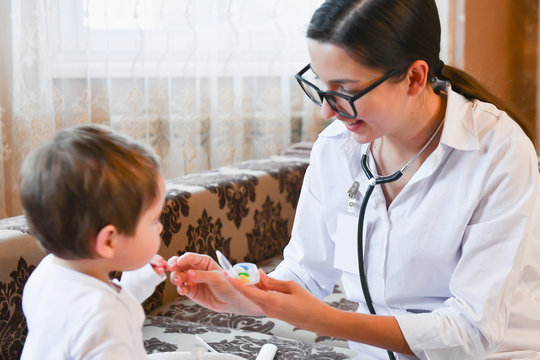 The doctor gives vitamins to the child. female doctor at home. the pediatrician gives vitamins to a small patient after the examination